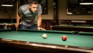 Pool player visualizing three-ball position patterns on a billiards table for strategic play