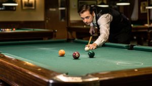 Pool player studying runout and position play patterns on a billiards table for advanced strategy