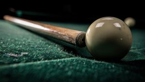 Close-up of a pool ball striking the rail cushion, highlighting the rebound mechanics of a bank shot.