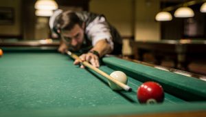 Pool player carefully reading the rail angles before executing a bank shot on a billiards table
