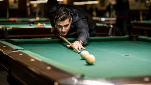 Pool player demonstrating strategic shot shape versus position play on a billiards table