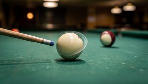 Close-up of a pool cue striking the cue ball to show spin transfer and throw effects with object ball